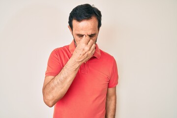 Middle age hispanic man wearing casual clothes tired rubbing nose and eyes feeling fatigue and...