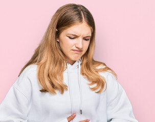 Beautiful young caucasian girl wearing casual sweatshirt with hand on stomach because indigestion, painful illness feeling unwell. ache concept.