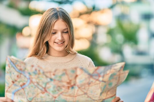 Beautiful caucasian tourist teenager smiling happy holding map at the city.