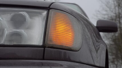 Close-up of the yellow front left light flashing on the car. During the day, the flashing yellow emergency lights or turns.