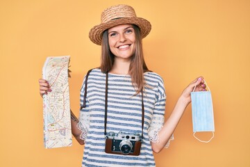 Beautiful caucasian tourist woman holding coronavirus safety mask smiling with a happy and cool smile on face. showing teeth.