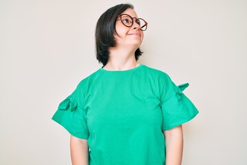 Brunette woman with down syndrome wearing casual clothes and glasses looking to side, relax profile pose with natural face and confident smile.