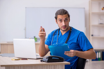 Fototapeta premium Young male doctor taking notes in the clinic