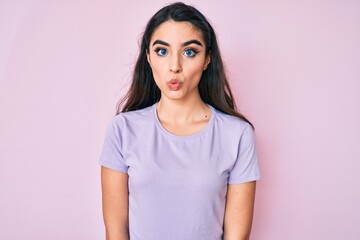 Fototapeta premium Brunette teenager girl wearing casual clothes scared and amazed with open mouth for surprise, disbelief face