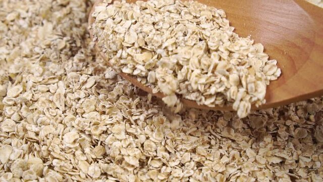 Wooden spoon is pouring oatmeal in slow motion. Close up. Healthy Vitamin Breakfast