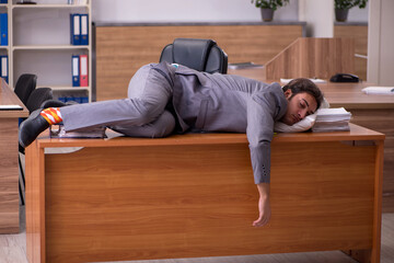 Young male employee sleeping at workplace