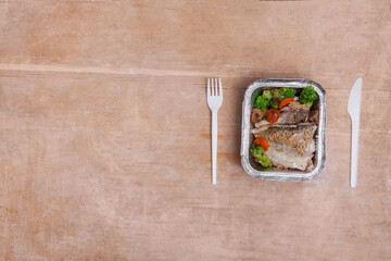 healthy food delivery or takeaway lunch box with fish, lettuce and tomato cherry