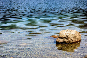 Rocks on the shore of a crystal clear lake.