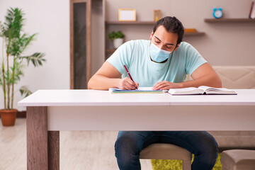 Young male student studying at home during pandemic
