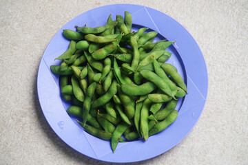 Ripe edamame is served on a purple plate