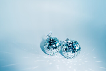 Fototapeta na wymiar Two disco balls on blue background with reflections, copyspace