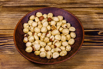 Ceramic plate with peeled hazelnuts on a wooden table