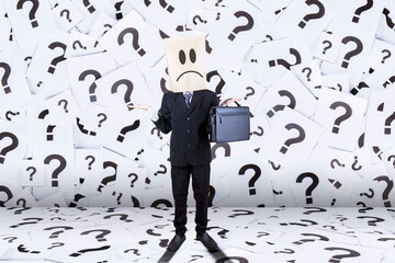 Businessman with cardboard head near question marks