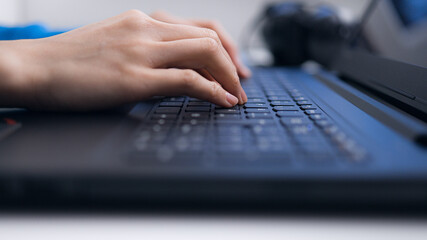 Woman taps on the keyboard of her laptop - close-up - home shooting