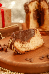 Slice of chocolate panettone  on wooden cutting board with christmas ornaments