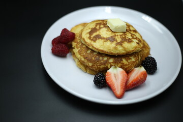Pancakes stack with different berries and honey isolated on black background