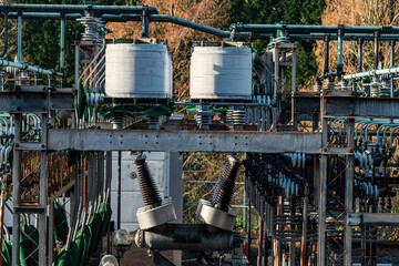 close up look a small size power plant in the city on a sunny day near a park with trees filled with autumn leaves