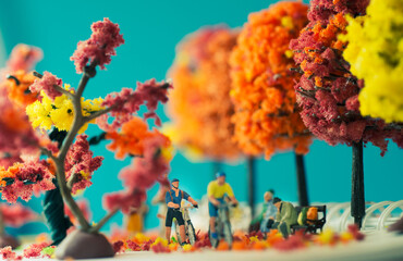 Side view miniature toy figurines of cyclist pushing a mountain bike in a park  in autumn, fall season or during cherry blossom season concept -  warm tone filter applied.