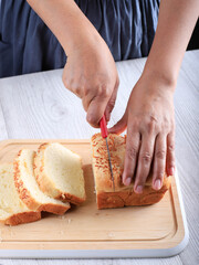 Female Home Chef Hand Cut Slicing Homemade White Japanese Brioche Loaf Bread on Wooden Board Using Knife