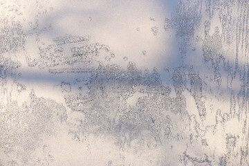 View of a window covered with frost after snowstorm. ice on the glass and shadows of tree branches. winter background. cold season weather.