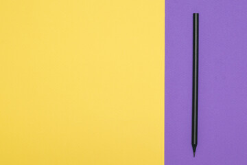 Black graphite pencil on a yellow and purple background.