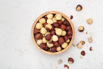 Hazelnuts in wooden bowl on marble background