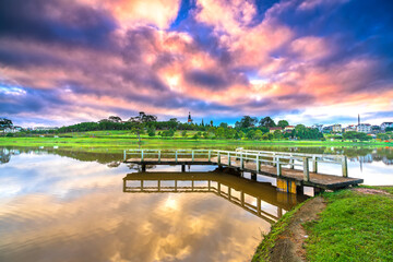 Fototapeta premium Dawn on love bridge overlooking the lake with the dramatic sky welcomes new day in the tourist city of Vietnam