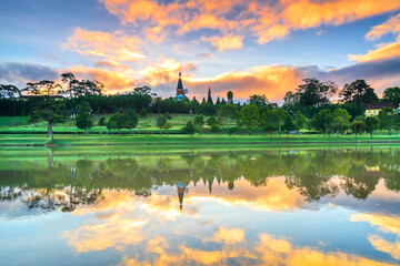 Fototapeta na wymiar Dawn by the large lake with impressive clouds reflecting into the colorful shimmering water to welcome the new day in the highlands of Vietnam