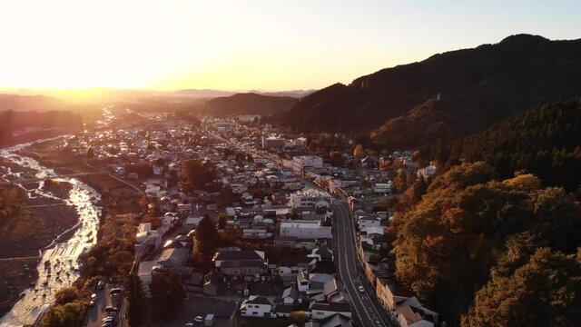 Slow aerial drone flight over beautiful town silhouette at sunrise with river