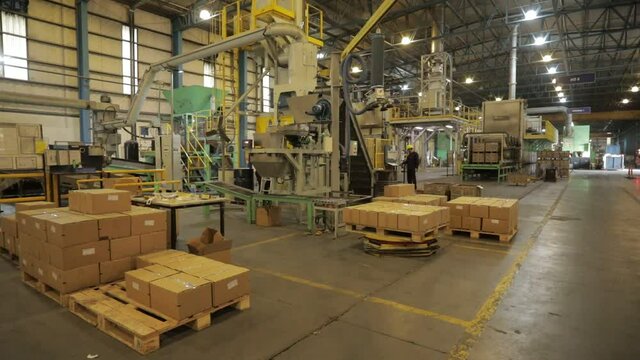 Wide shot of a factory during packaging process with machines and several boxes arranged on pallets