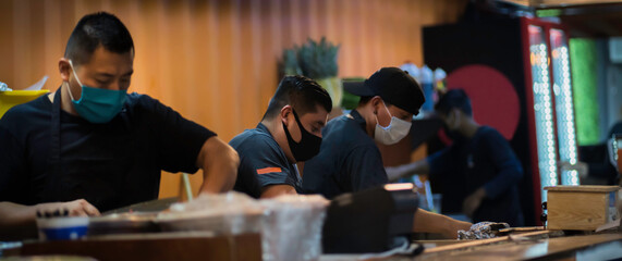 Three mexican taqueros who prepares tacos al pastor in Taqueria
