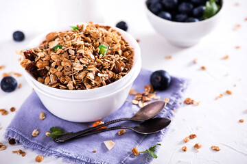 Muesli with blueberris in a bowl   on white wooden background. Delicious and healthy breakfast.