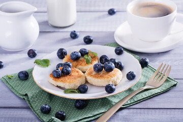 Cottage cheese pancakes, syrniki on white plate with  fresh blueberries. Healthy and delicious morning breakfast.Top view, copy space.