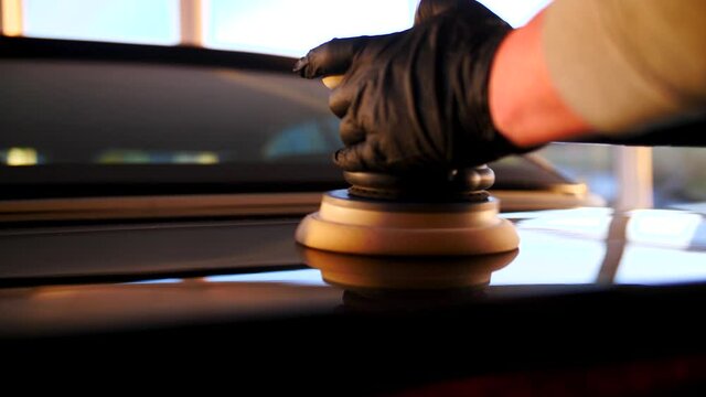 Auto polieren folieren lackieren Werkstatt Arbeit KFZ Aufbereitung intensiv Pflege und Kratzer Dellen entfernen mit Einweg Handschuhen bei Sonnenuntergang kurz vor Feierabend 4k