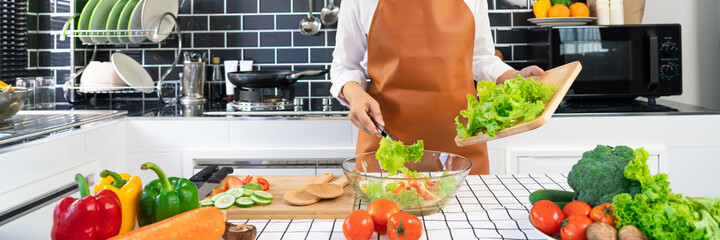 woman in the process of preparing healthy food Vegetable Salad mixing salad wooden spoon in kitchen at home Dieting Concept