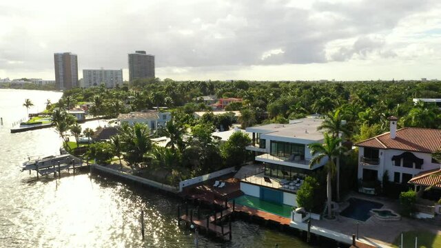 Aerial video sun shining over water with waterfront mansion homes in Miami 4k