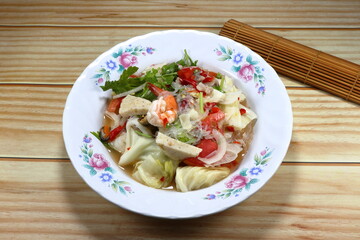 Spicy vermicelli salad mixed with fresh vegetable and steamed seafood meat on the plate. Famous traditional appetizer menu in Asia restaurant. 