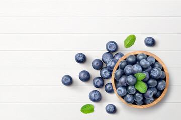 Naklejka na ściany i meble Flat lay (top view) of Blueberries in wooden bowl on white wood background.
