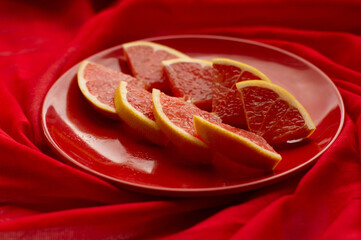 Pieces of red orange on a red plate and red tablecloth