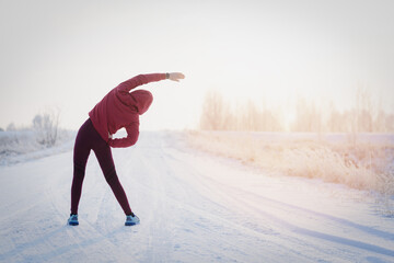 Fitness woman runner on sunny winter road.
