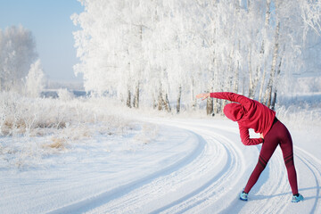 Fitness woman runner on sunny winter road.