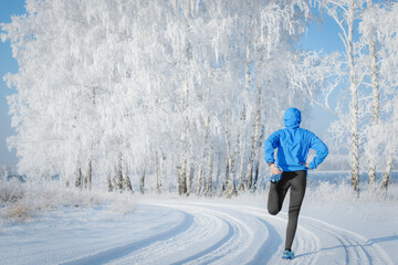 Fitness woman runner on sunny winter road.