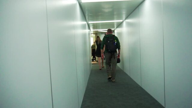 Slow motion follow shot of person walking out from plane into terminal with moody lighting