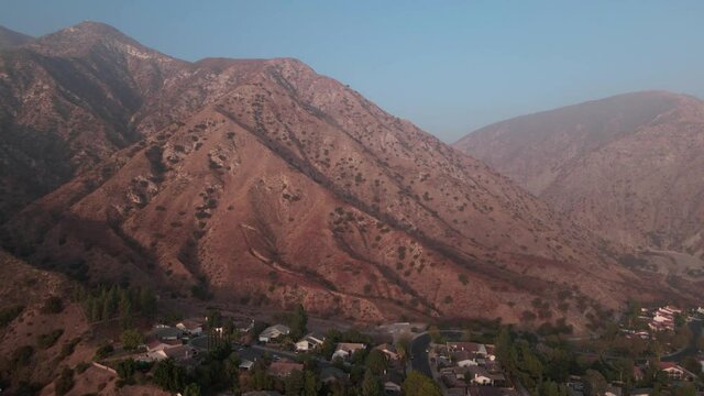 Aerial shot push back of Sylmar mountains, houses and park in San Fernando Valley, California during sunset. Shot in 4k