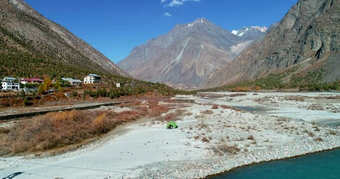 Adventurous solo camping in a beautiful mountain landscape close to river stream. Dreamy Himalayan valley in Asia