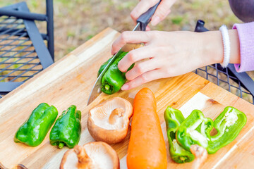 屋外でバーベキュー用の野菜を準備、包丁で切っている様子