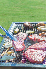 屋外のオープングリルで牛肉を網焼きしている様子