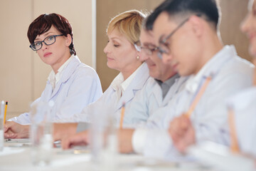 Pretty young pharmacist in glasses attending conference for specialists