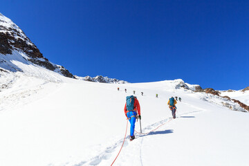 Rope team mountaineering with crampons on glacier Sexegertenferner towards Sexegertenspitze and...