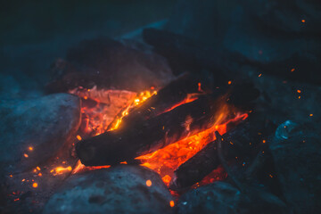 Vivid smoldered firewoods burned in fire close-up. Atmospheric background with orange flame of...